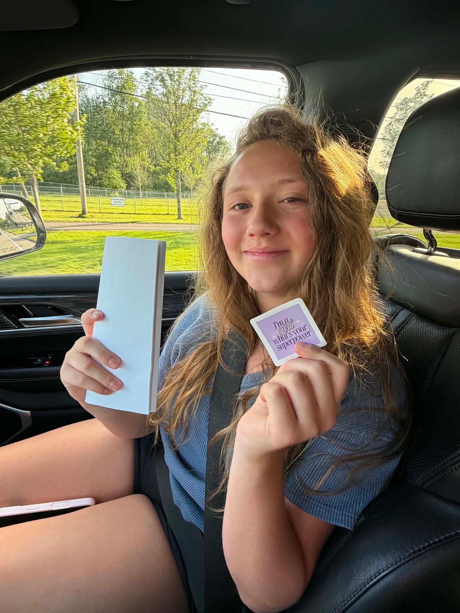 Veda holding her Big Sister Letter and an affirmation card in the car