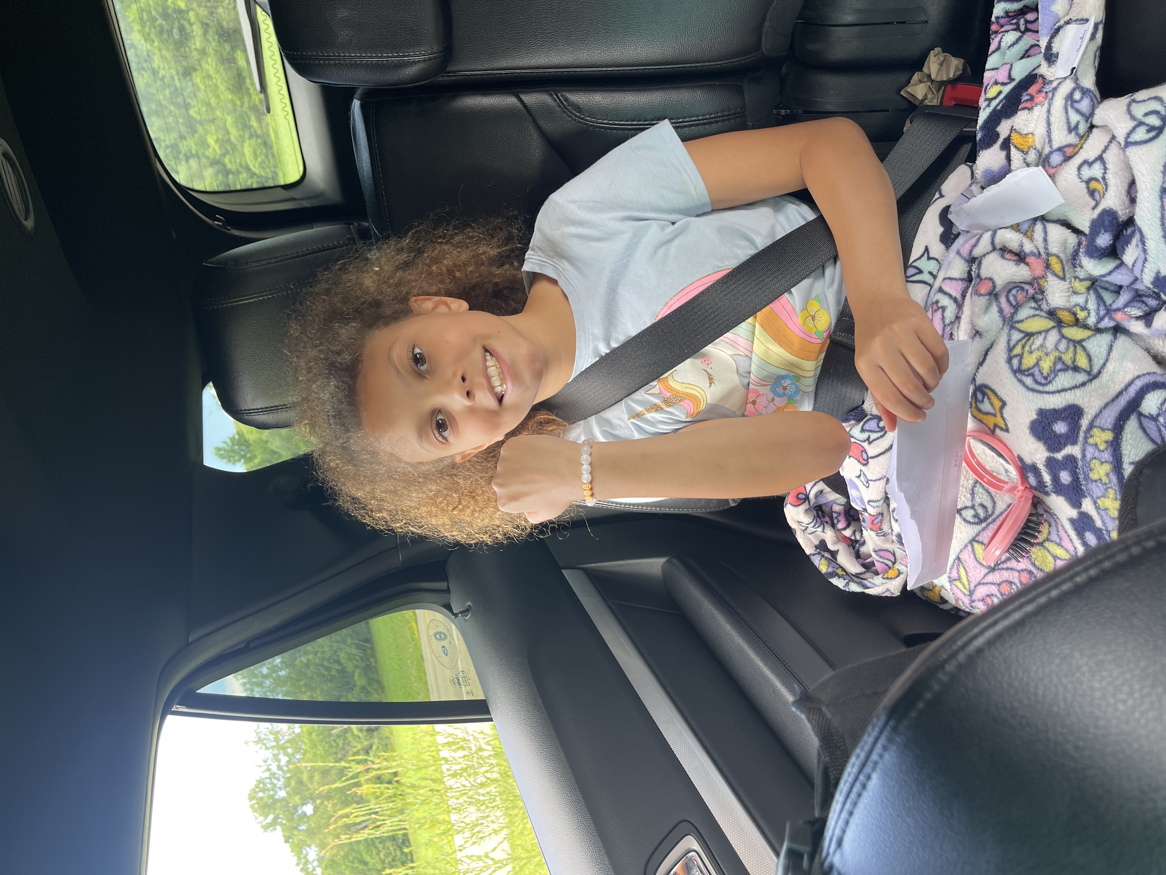 Payton reading her Big Sister Letter in the back seat of the car